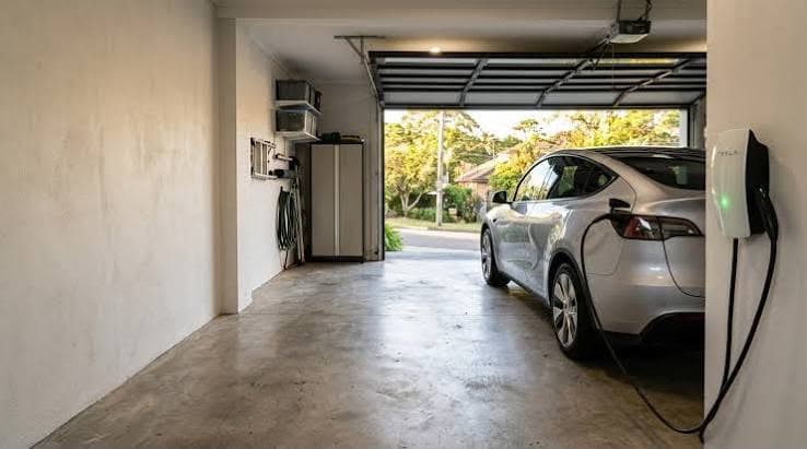 EV charger mounted on a garage wall with a car plugged in and charging